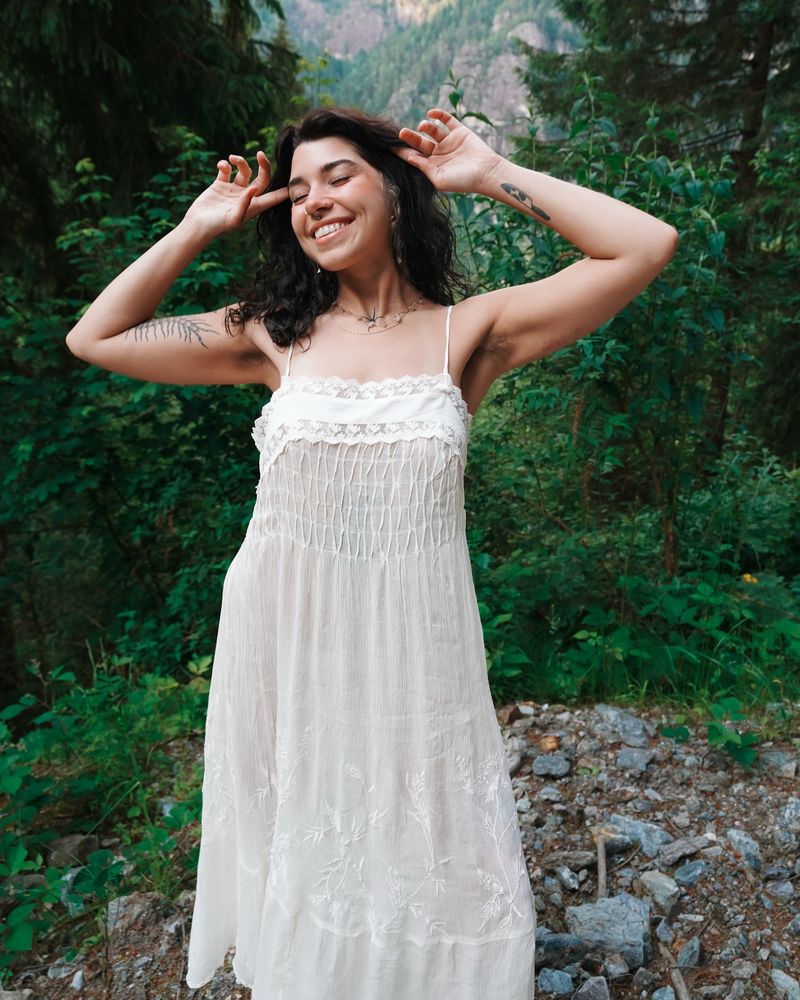 Ivy smiling in a white sundress in the mountains